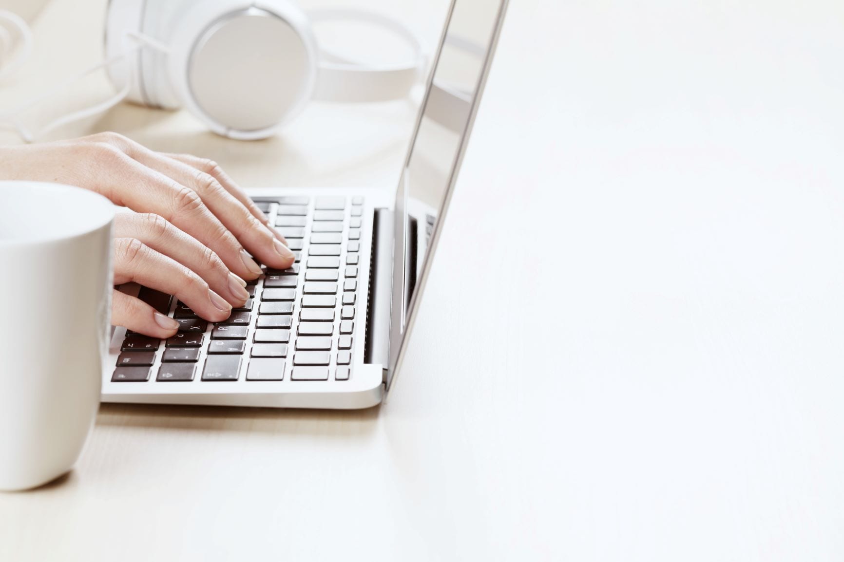 A close-up shot of a person's hands typing on a laptop keyboard with precise hands and a white desk space as image for bounce rate