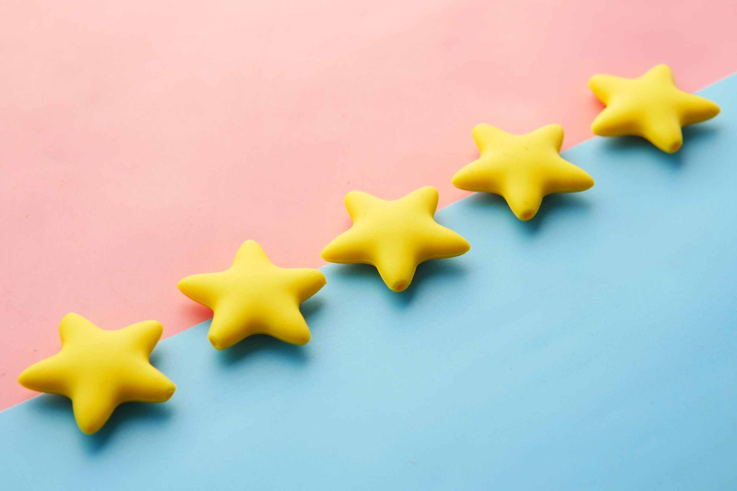 Five yellow stars lined diagonally on a pink and light blue background