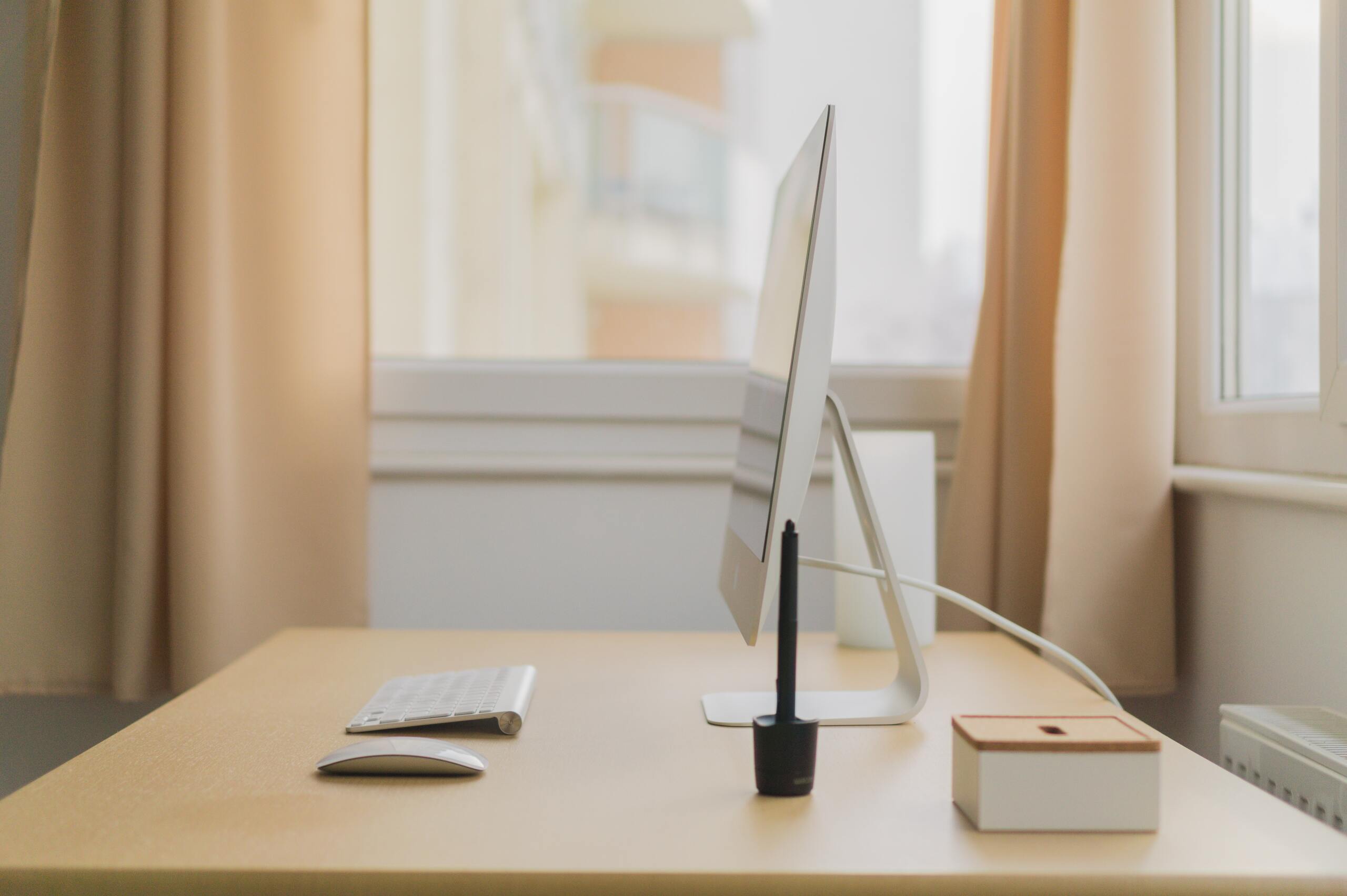 A minimalist work desk with a computer and wireless keyboard and mouse, the elegance of minimalism in a workspace