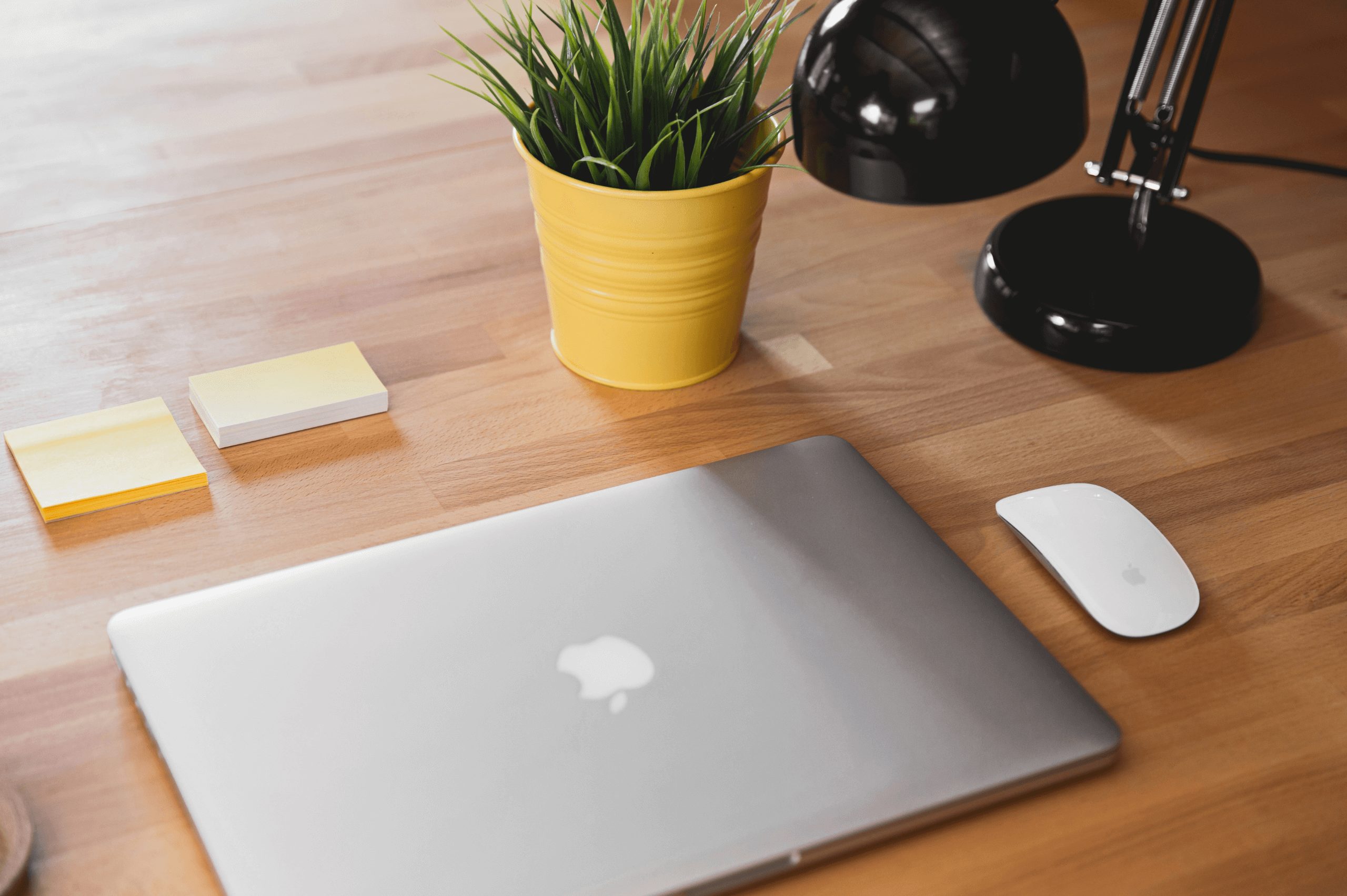 Apple laptop and mouse on a brown wooden table